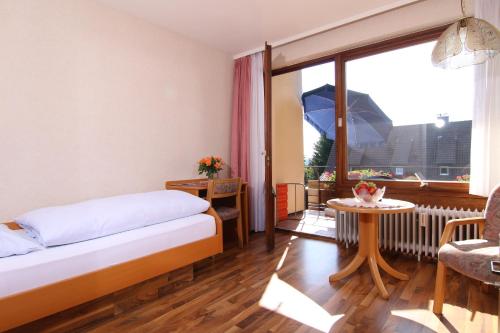 a bedroom with a bed and a table and a window at Gästehaus Schmid-Lopez in Bad Wildbad
