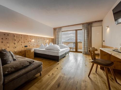 a large bedroom with a bed and a couch at Hotel Elisabeth Panorama in Antermoia