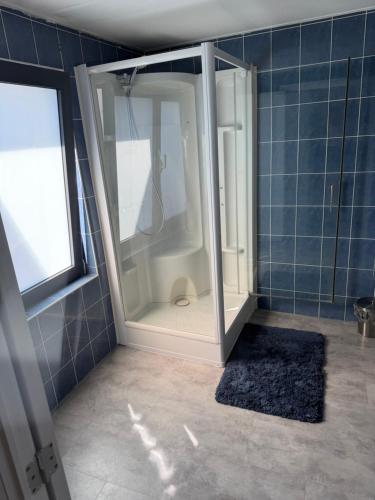 a shower in a bathroom with a blue tiled wall at 1 Chambre Moyenne avec television in Charleroi