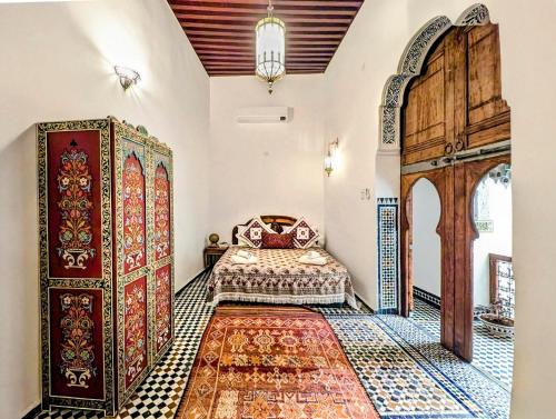 a bedroom with a bed and a wooden door at Rooms in Dar Drouj, a special 14th century house Riad in Fez