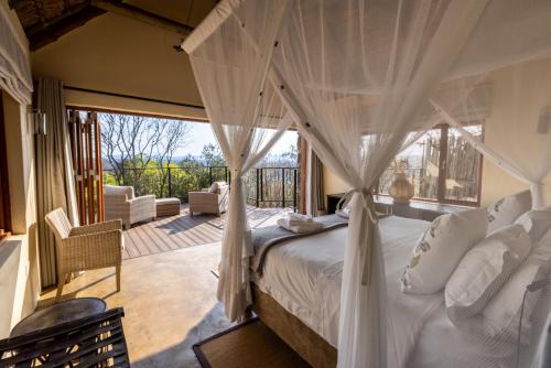 a bedroom with a canopy bed and a balcony at Magari Safari Lodge in Vaalwater