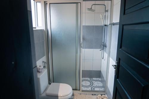 a bathroom with a toilet and a glass shower at Explorers Hub in Kampala