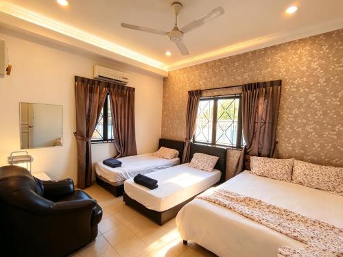 a bedroom with two beds and a couch and a chair at MELAKA BEACH VILLA ( B TYPE ) in Malacca