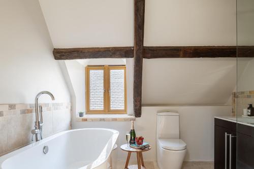 a white bathroom with a tub and a toilet at Serenity in Painswick