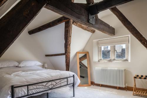 a bedroom with a bed and a window and wooden beams at Serenity in Painswick