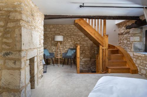 a bedroom with a stone wall and a staircase with blue chairs at Tranquility House in Painswick