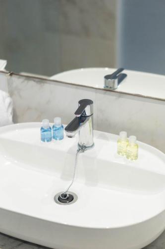 a bathroom sink with a faucet and three bottles at Golf Residence- Families and Couples Only in Hammam Sousse
