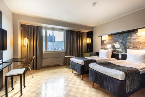a hotel room with two beds and a desk at Scandic Tampere Hämeenpuisto in Tampere