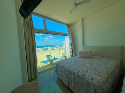 a bedroom with a bed and a view of the beach at Suítes Pitangueiras - POUSADA FRENTE MAR in Guarujá