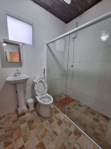 a bathroom with a shower and a toilet and a sink at Suítes Pitangueiras - POUSADA FRENTE MAR in Guarujá