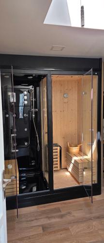 a room with glass doors and a room with a wooden floor at Lodge avec piscine chauffée privative et ou Studio avec son SPA, SAUNA HAMAMM privatifs in Cepoy