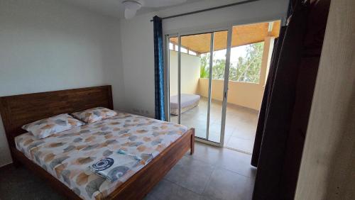 a bedroom with a bed and a door to a balcony at Le chant des vagues in Saint-Philippe