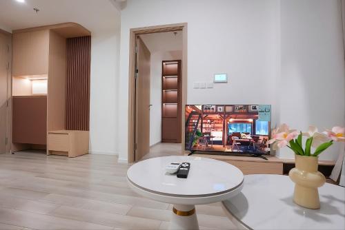 a living room with a white table and a tv at Ataraxia Residences in Gò Công