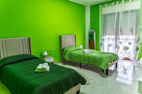 a green bedroom with two beds in front of a window at Gold House in Lungro