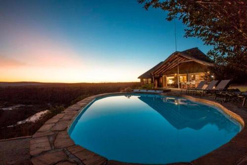 a large blue swimming pool in front of a house at Magari Safari Lodge in Vaalwater