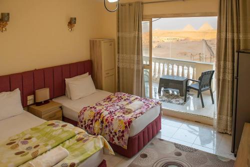 a bedroom with two beds and a balcony with a view at Pyramita luxury hotel in ‘Ezbet `Abd el-Ḥamîd