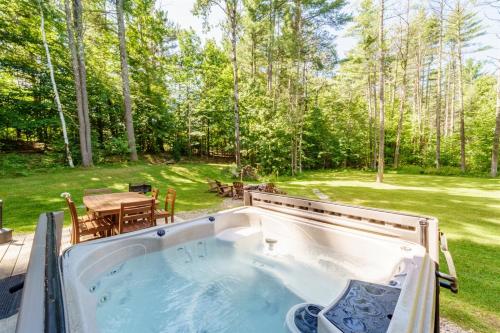 a hot tub in a backyard with a table at Adirondack Retreat Near Whiteface and Lake Placid in Wilmington