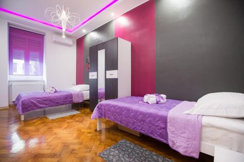 a room with two beds and a purple wall at Apartment Center Four stars in Zagreb