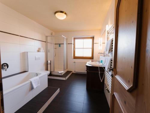a bathroom with a tub and a sink at Alpenhotel Ernberg in Reutte