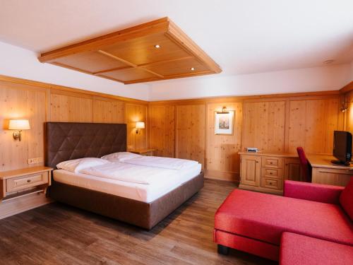 a bedroom with a large bed and a red couch at Alpenhotel Ernberg in Reutte