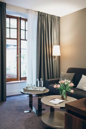 a living room with a couch and tables and a window at Hôtel des Voyageurs Boutique in Lausanne