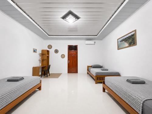 a room with three beds and a ceiling at Surak Villa Mentawai in Katiet