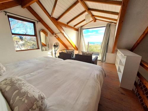 a large bed in a room with large windows at Saint Anna Beach House in St. Helena Bay