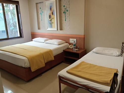 a bedroom with two beds and a window at Sai Palace Express(Shirdi) in Shirdi