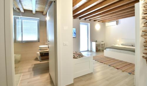a white room with a bed and a bathroom at Alla Corte del Gallo in Tricesimo