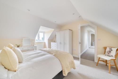a white bedroom with a large bed and a chair at The Donkey Shed in Sherborne