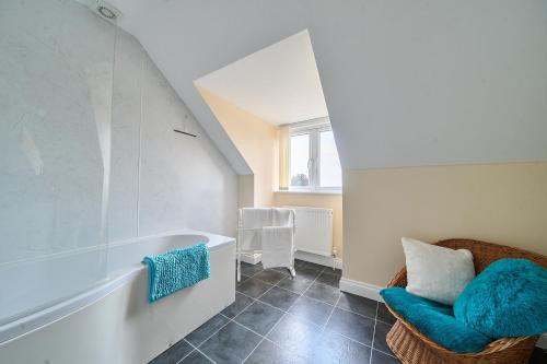 a bathroom with a bath tub and a chair at The Donkey Shed in Sherborne