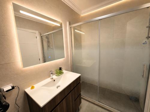 a bathroom with a sink and a shower with a mirror at ENJOY POOL, BEACH and more at this nice 2bedroom apartment only 3 minutes from Mareta's Beach in Sagres