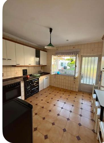 a kitchen with a tiled floor and a window at El Rincón de pedreña in Pedreña