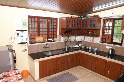 a kitchen with wooden cabinets and a sink at CITADEL HOLIDAY HOME in Vythiri