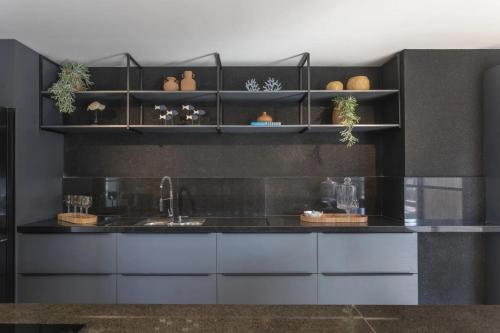 a kitchen with a counter with a sink and shelves at Ancorar Hospedagens in João Pessoa