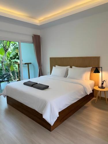 a bedroom with a large white bed and a window at Zerohouse in Ban Bang Bao