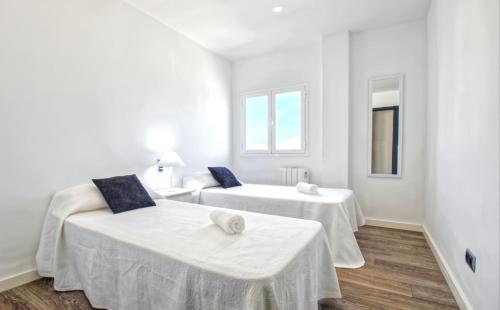 a white room with two beds and a mirror at Son Baulo in Can Picafort