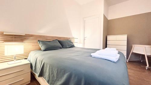 a bedroom with a bed and a nightstand with towels on it at BorgoLuce Spacious Apt - FREE Parking - Near Airport & Center in Bergamo