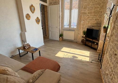 a living room with a couch and a tv at L'Écrin de Pierre - Gare & Centre à pied - Charme & Calme in Mâcon