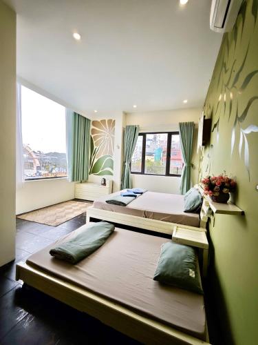 a bedroom with two beds and a large window at The Little Leaf Hostel - Restaurant & Rooftop Bar CatBa in Cat Ba