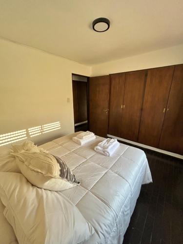 a bedroom with a large white bed with wooden cabinets at Magnolia Tempo in Esquel