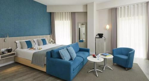 a hotel room with a bed and blue chairs at Occidental Faro in Faro
