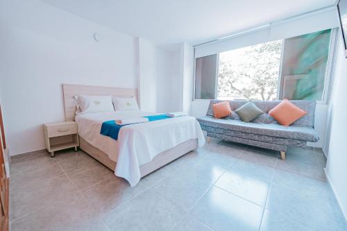 ein Schlafzimmer mit einem Bett, einer Couch und einem Fenster in der Unterkunft Apartamento Edificio Neon Centro in Ibagué