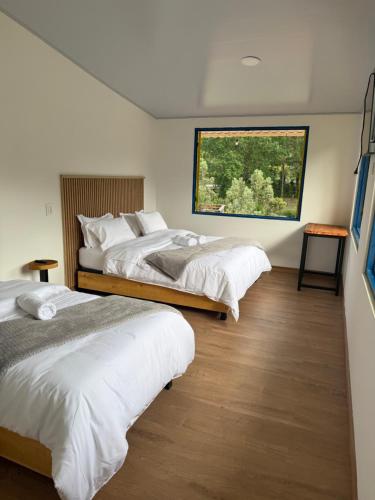 ein Schlafzimmer mit zwei Betten und einem großen Fenster in der Unterkunft Salento River Hotel in Salento