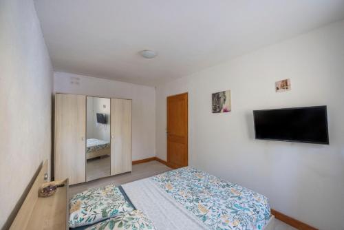 a bedroom with a bed and a flat screen tv at Appartement Aléria avec jardin in Aléria