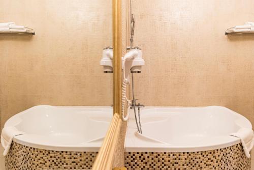 a bathroom with a bath tub and a sink at Grand Hotel Traian in Iaşi