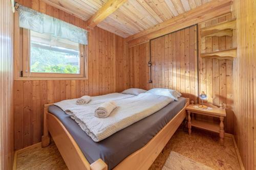a bed in a wooden room with a window at 3 Rivers Beehive cabin on a farm in Radovljica