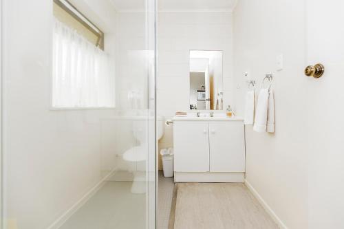 La salle de bains blanche est pourvue d'un lavabo et d'une douche. dans l'établissement Foreshore Motor Lodge, à Petone