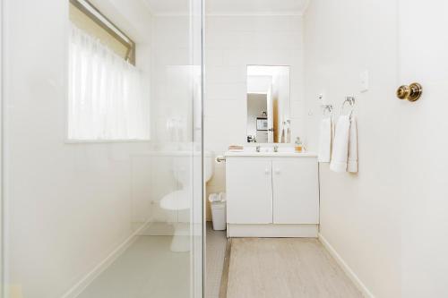 a white bathroom with a sink and a shower at Foreshore Motor Lodge in Lower Hutt