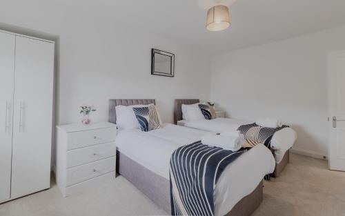 a white bedroom with two beds and a dresser at Executive 2BR Business & Contractor Stay in Weston-super-Mare